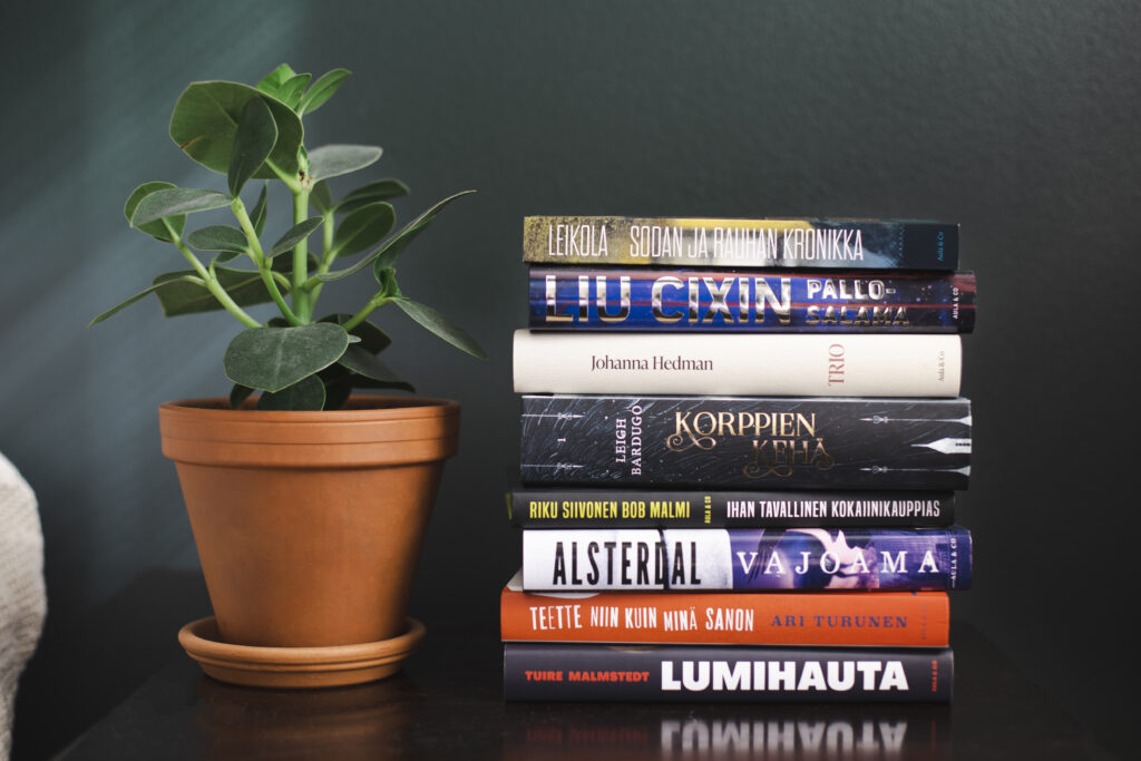 Viherkasvi ja kirjapino vihreää seinää vasten.